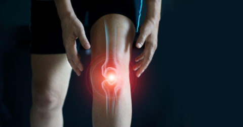 Elderly Woman Suffering From Pain In Knee. Tendon Problems And Joint Inflammation On Dark Background.